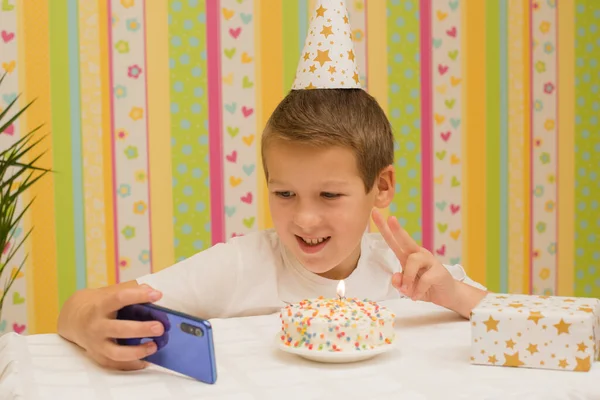 holiday, birthday of a teenager school boy, a child of 10 years old on the table a cake with a candle and a gift, the theme of the holiday without friends in quarantine