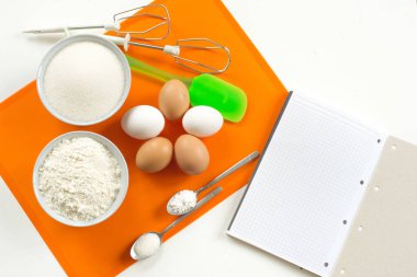 Tarif adım adım bisküvi için bir yan turuncu halı üzerinde ürün düzeni 5 yumurta, un, vanilya şekeri, şeker, kabartma tozu, spatula ve mikser üst görünümü için çırpıcı