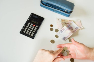 Yaşlı bir kadının elinin yakın plan fotoğrafı. Arka planda Rus rublesi var. Arka planda, beyaz masa arkasında, mesaj atmak için kullanılan ilaçlar var.