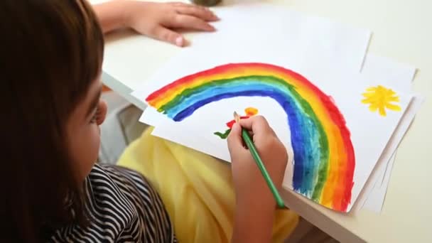 Eine 7-jährige Schülerin malt einen Regenbogen als Symbol für das Ende einer Pandemie — Stockvideo