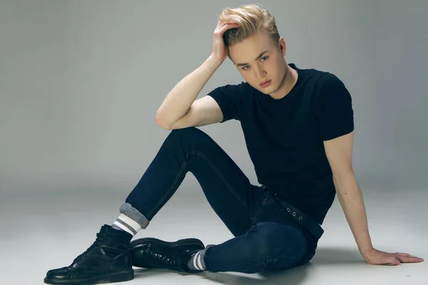 Young male model  sitting on teh floor looking at the camera