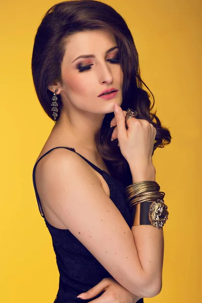 Sensuelle belle femme brune posant en robe noire et or — Photo