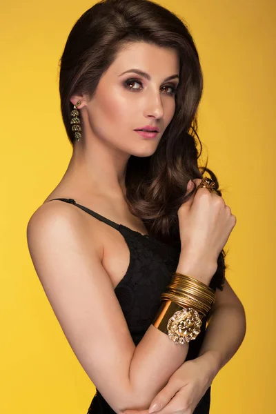 Sensual hermosa mujer morena posando en vestido negro y oro Imagen De Stock