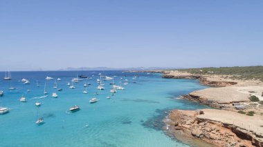 İnanılmaz turkuaz deniz, küçük bir uçurumun önünde demirli tekneler.