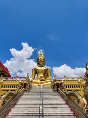 Kuzey Tayland 'da bir tapınaktaki büyük altın Buda heykeli. - Mavi gökyüzü ve bulutlar.