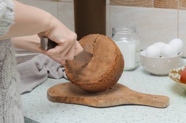 Bıçakla kesilmiş kadın elleri iştah açıcı, çıtır çıtır ev yapımı çavdar ekmeği ahşap bir kesim tahtası ve açık bir masa üstü.