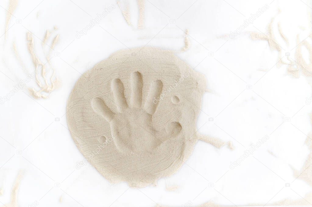 imprint of a childs hand on natural sand in a sandbox for drawing