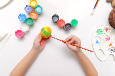 Paskalya için hazırlanıyorum. Çocuklar yumurtanın üstüne resim yapar. Yukarıdan beyaz arkaplanda görüntüle