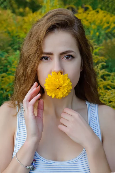 Retrato de uma menina caucasiana com uma flor amarela na boca — Fotografia de Stock