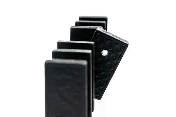 Una cola de siete dominó alineados con un impaciente dominó espiando. De cerca. — Foto de Stock
