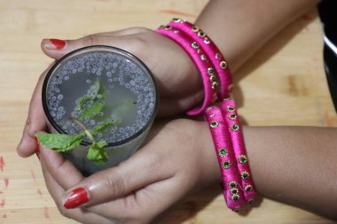 Sırılsıklam tatlı fesleğen ya da tukhmaria ya da falooda tohumları ya da sabja tohumları beyaz arka planda izole edilmiş bir kâse kenarında.