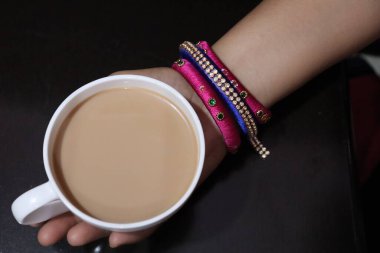 Süslü bir fincanda sıcak Masala Çayı ve beyaz arka planda çay tabağı.