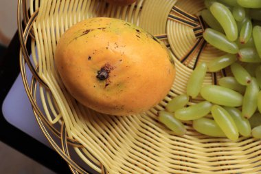 Beyaz zemin üzerinde taze sarı mango ve üzüm meyveleri izole edilmiş.