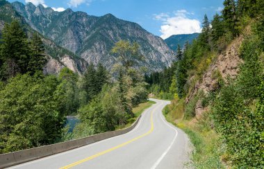 Scenic Road in British Columbia:  A winding tree-lined road passes a stream and rocky outcroppings in its climb through the mountains northeast of Vancouver, Canada.