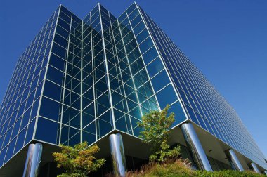 Modern Office Building: Cam ve metal projelerdeki temiz çizgiler yukarı çıkıyor ve açık mavi bir gökyüzüne karışıyor.