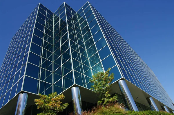 Modern Office Building: Clean lines in glass and metal project upward and blend into a clear blue sky.