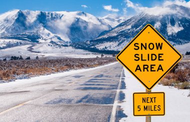Snow Slide Area Sign:  Motorists are warned of dangerous driving conditions on a road leading into the Sierra Nevada Mountains.