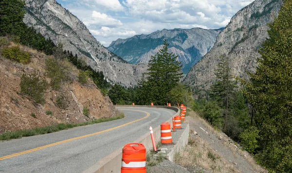Mountain Road Repairs:  Orange barrels mark the edge of a road under repair in the mountains of British Columbia.