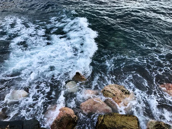 Dalgalar Karadeniz 'de kayalara çarpıyor. Dalgalar mavi gökyüzünün altındaki kayalarda kırılır.