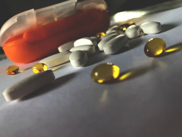 Masaya bir sürü vitamin saçılmış. Arka planda makine kutusu var.
