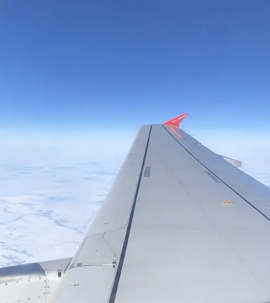 Fotoğraf, kanadın tam üstündeki bir uçak penceresinden çekilmiş. Uçak penceresinden gelen bulutlar