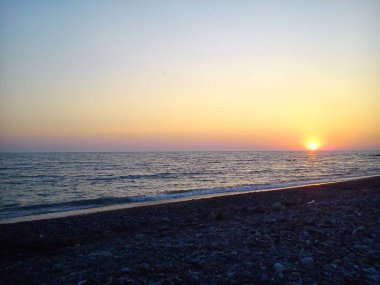 Denizde gün batımı. Güneş ufuktan batıyor. Sakin deniz