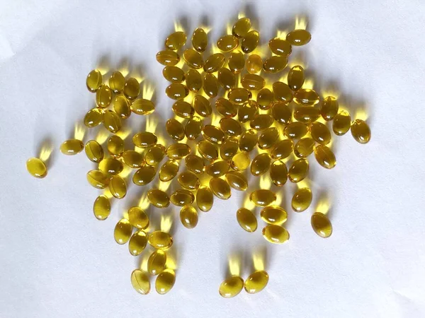 Beyaz arka planda izole edilmiş birçok tablet var. Balık yağı, omega-3 ve D3 vitamini kapsüllerinin üst görünümü.