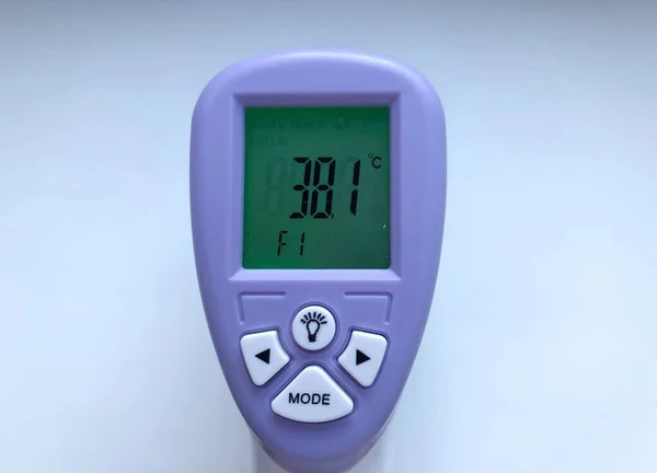 Electronic thermometer in hand. A medical instrument, an electronic digital thermometer, is used to measure a patient\'s temperature in a hospital. Close-up, in hand thermometer on white background.