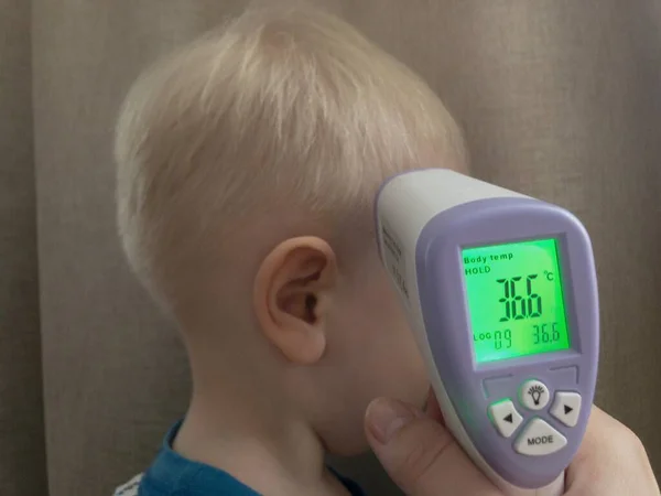 Barnens temperatur mäts med en elektronisk termometer. Royaltyfria Stockfoton