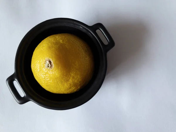 Tabakta sarı bir limonun yakın çekimi. Beyaz arkaplanda.