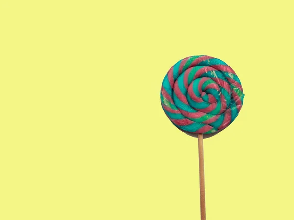 Sarı arka planda izole edilmiş büyük renkli bir lolipop..