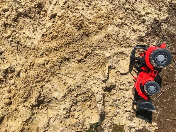 Kum havuzundaki kum. Çocuk oyuncağı, kumda kırmızı traktör. Bebeğin oyuncakları dışarıda.