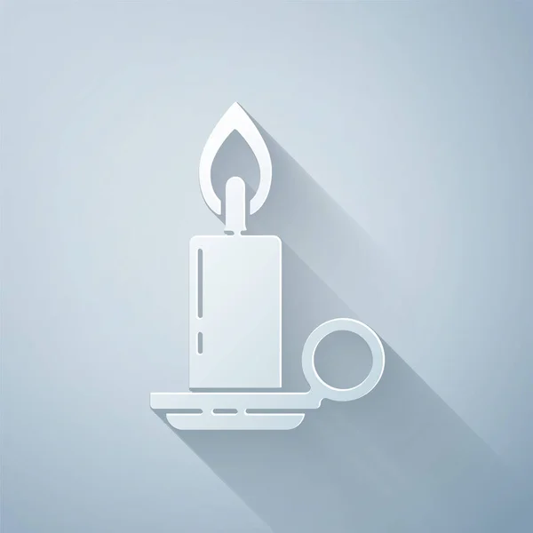 Paper cut Burning candle in candlestick icon isolated on grey background. Cylindrical candle stick with burning flame. Paper art style. Vector Illustration — ストックベクタ