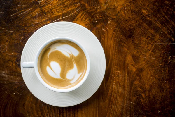 Taza de café latte caliente sobre un fondo de madera . — Foto de Stock