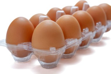 Beyaz arka planda şeffaf plastik bir kutuda tavuk yumurtası.