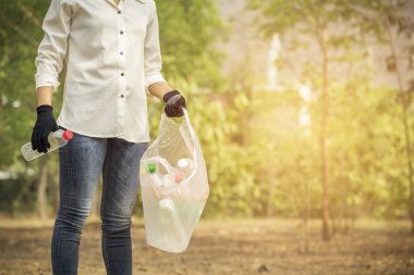 Volunteer woman collecting PET plastic bottle garbage in park for recycle. Volunteer and Save Environmental concept.