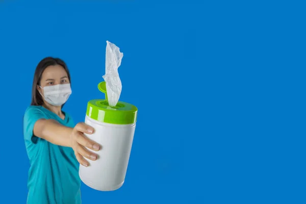 Female hold and handing wet wipes or wet tissues on blue background.