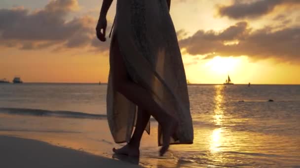 ビーチで夕日の美しい女性のドレスは裸足で歩く — ストック動画