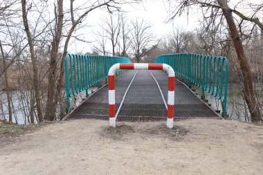 Parkta kışın nehrin üzerinde demir köprü