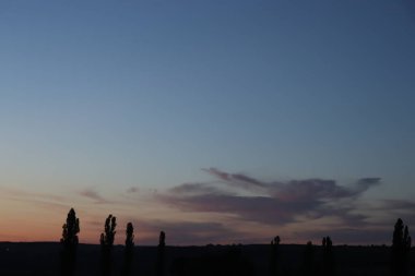Bulutlu bir gökyüzünde gün batımı, yazın son günleri.