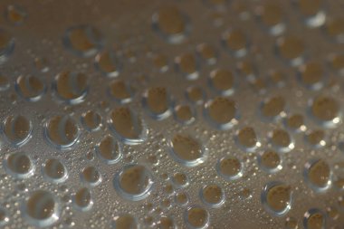 Su şeffaf plastik bir yüzeye düşer, suyun makro görüntüsü