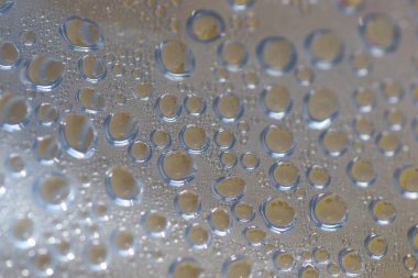 Su şeffaf plastik bir yüzeye düşer, suyun makro görüntüsü