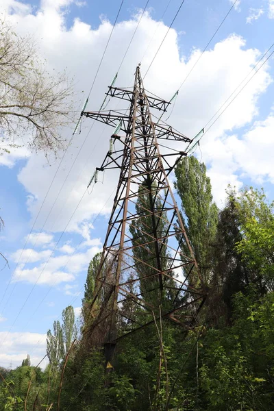 塔は高電圧線青い空の下の森の金属製の塔 — ストック写真