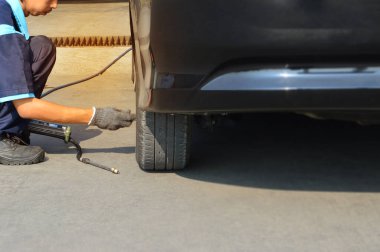 Tamirci hava basıncını ölçüyor ve müşterinin lastiklerini dolduruyor.