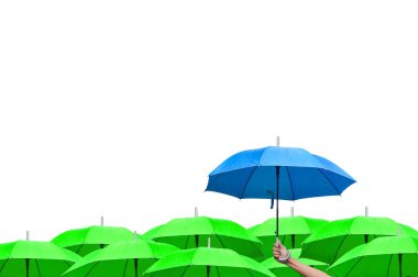 İş dünyasındaki liderliğe adım atmanın farkı. Birçok yeşil şemsiye üzerinde mavi bir şemsiye tutan bir adam eli. Yağmur yağıyor. yan görünüm.