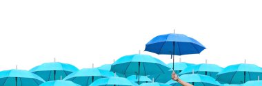 İş dünyasındaki liderliğe yükselme farkı. Gökyüzü şemsiyeleri arasındaki mavi şemsiye. Yağmurda birçok şemsiye üzerinde mavi bir şemsiye tutan bir adam eli. yan görünüm.