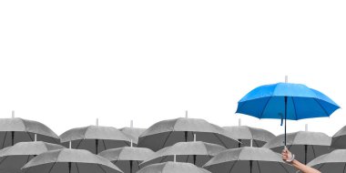Beyaz arka planda siyah şemsiyeler üzerine mavi şemsiye. İş dünyasına liderlik etmenin farkı, yağmurda elinde mavi şemsiye tutan bir adamın elidir. yan görünüm.