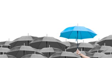 Beyaz arka planda siyah şemsiyeler üzerine mavi şemsiye. İş dünyasına liderlik etmenin farkı, yağmurda elinde mavi şemsiye tutan bir adamın elidir. yan görünüm.