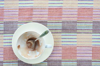 Üst manzara, renkli kumaş arka planda bir fincan kahve içmeyi bitirdim.