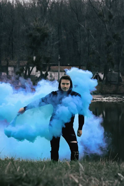 Guy with colorful smoke in forest at morning — Stock Fotó